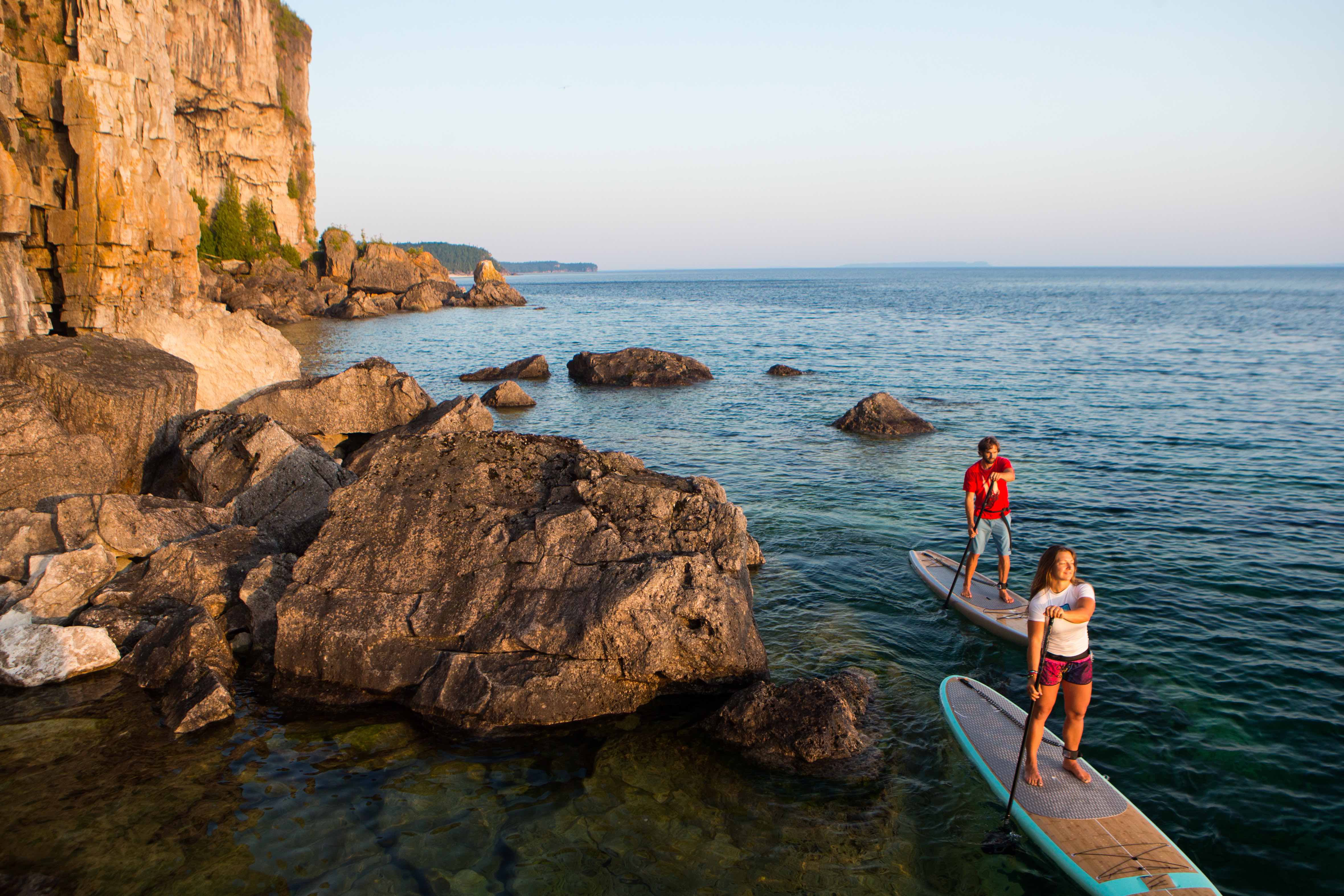 Attractive Young couple Stand Up Paddle Boarding, active beach lifestyle